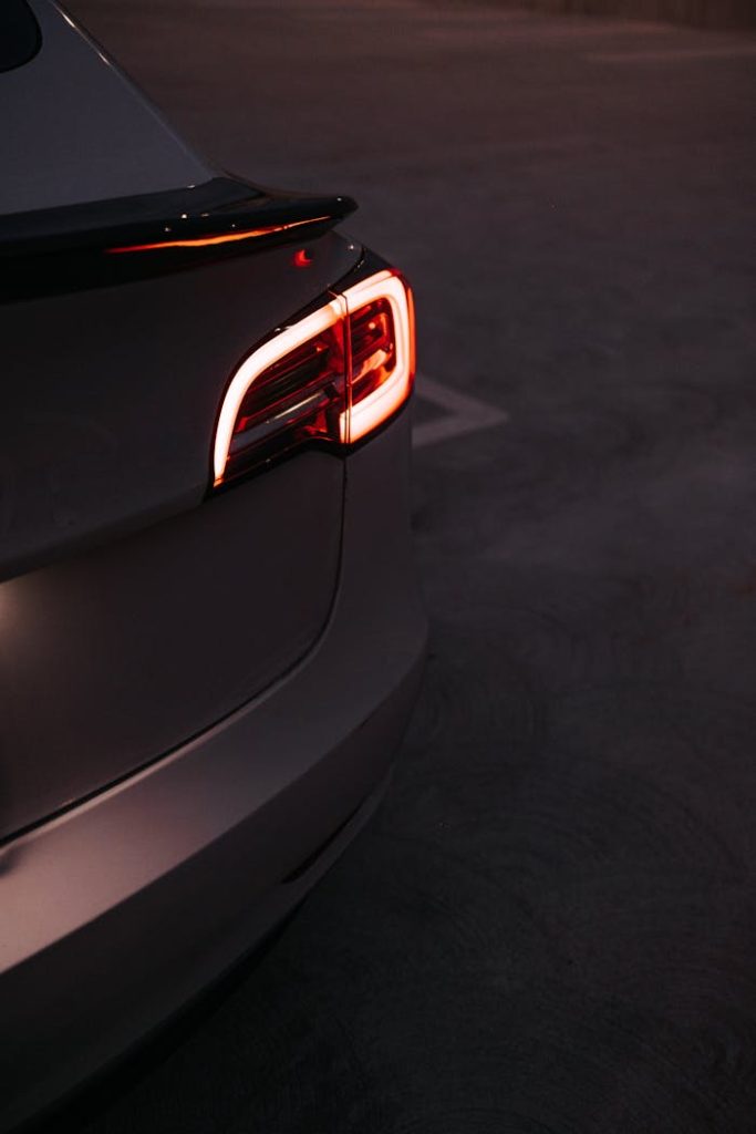 Close-up of a modern cars illuminated taillight at night in an urban setting.